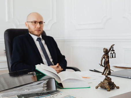 Attorney sitting at a desk with legal documents and Lady Justice statue, discussing the benefits of a revocable living trust.